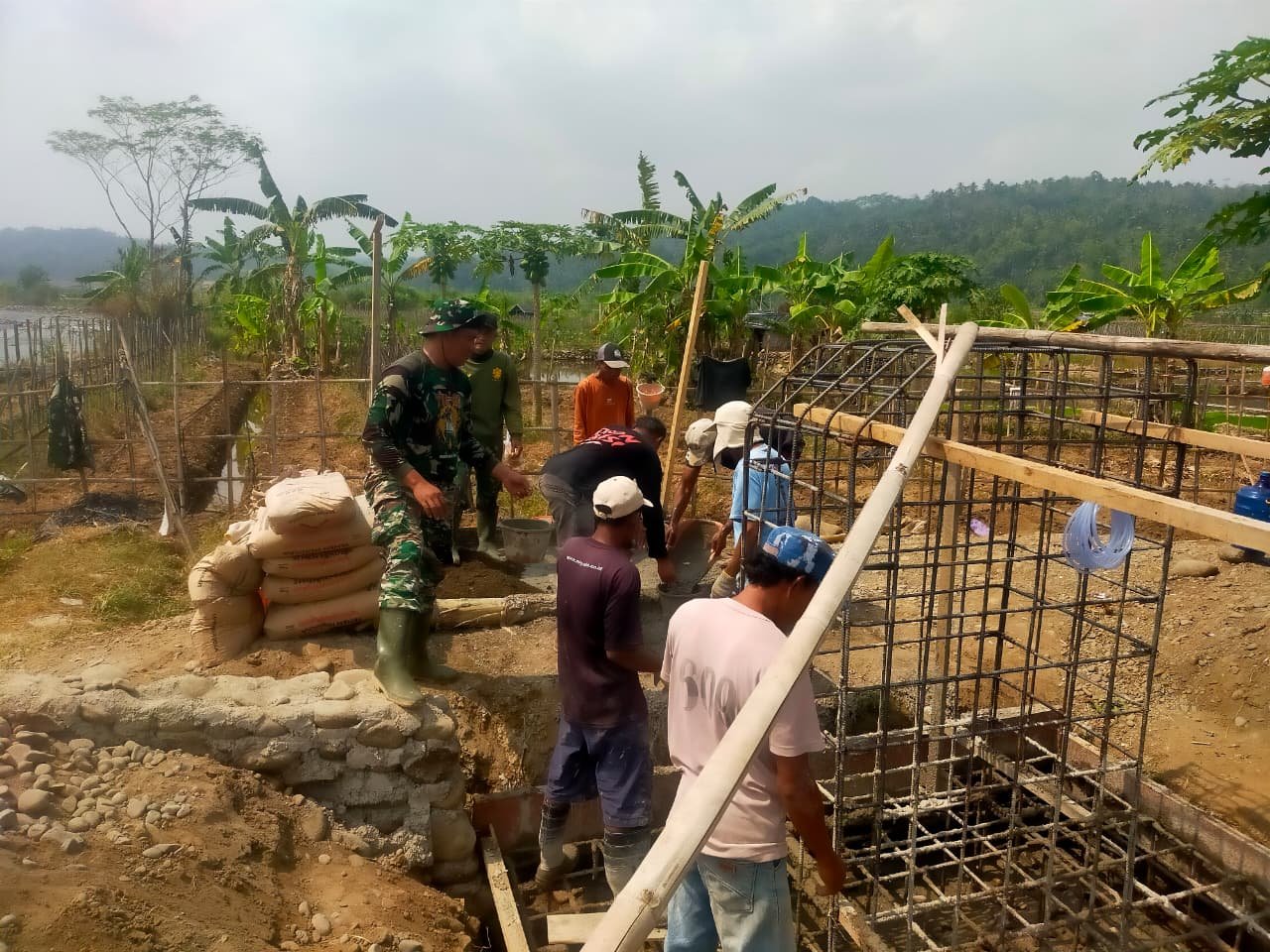  Silih Berganti, TNI dan Warga Aduk Material untuk Cor Pondasi Jembatan Garuda di Wanogara Wetan